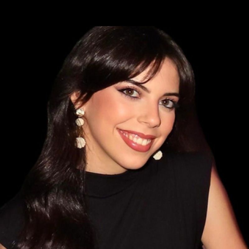 Hombre de ojos marrones, barba y sonriente; viste camisa azul claro y tirantes.