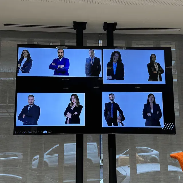 En una pantalla aparecen ocho personas en una videoconferencia. Están vestidas de forma profesional sobre un fondo blanco.