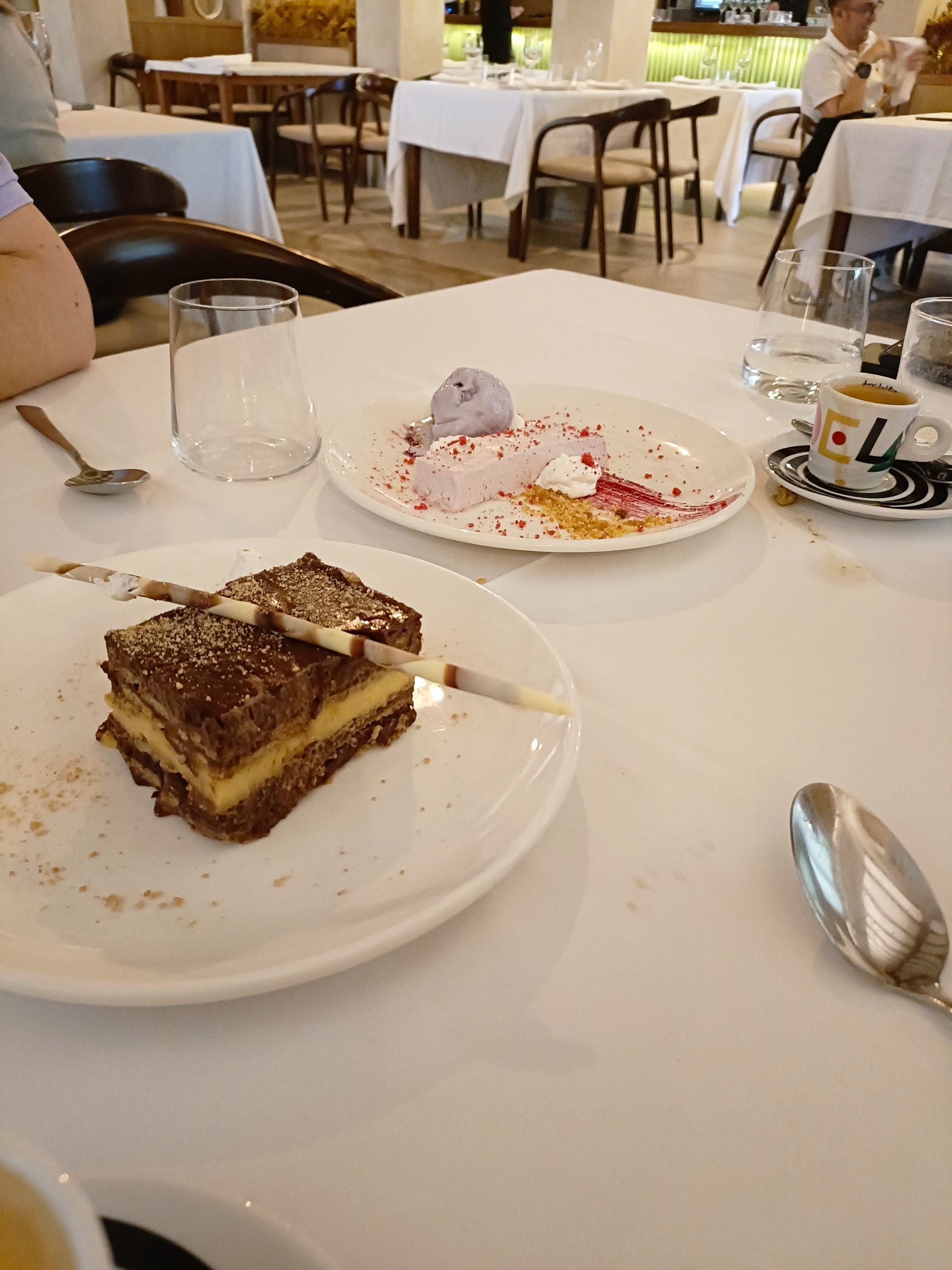 Postres en platos blancos sobre una mesa de restaurante: pastel y helado.