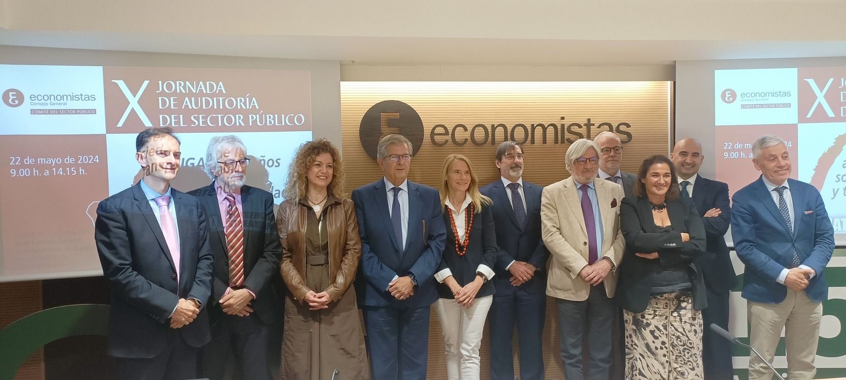 Grupo de personas de pie frente a una pancarta. Se encuentran en un evento con la palabra 