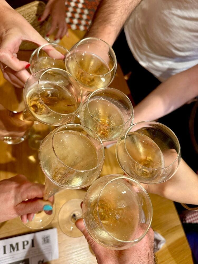 Personas brindando con copas de champán en una mesa; iluminación cálida.
