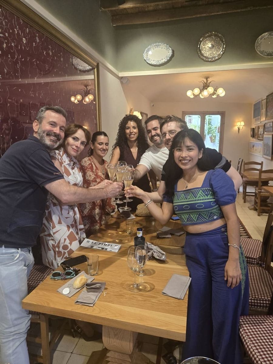 Grupo de personas brindando con copas alrededor de una mesa de madera en un restaurante.