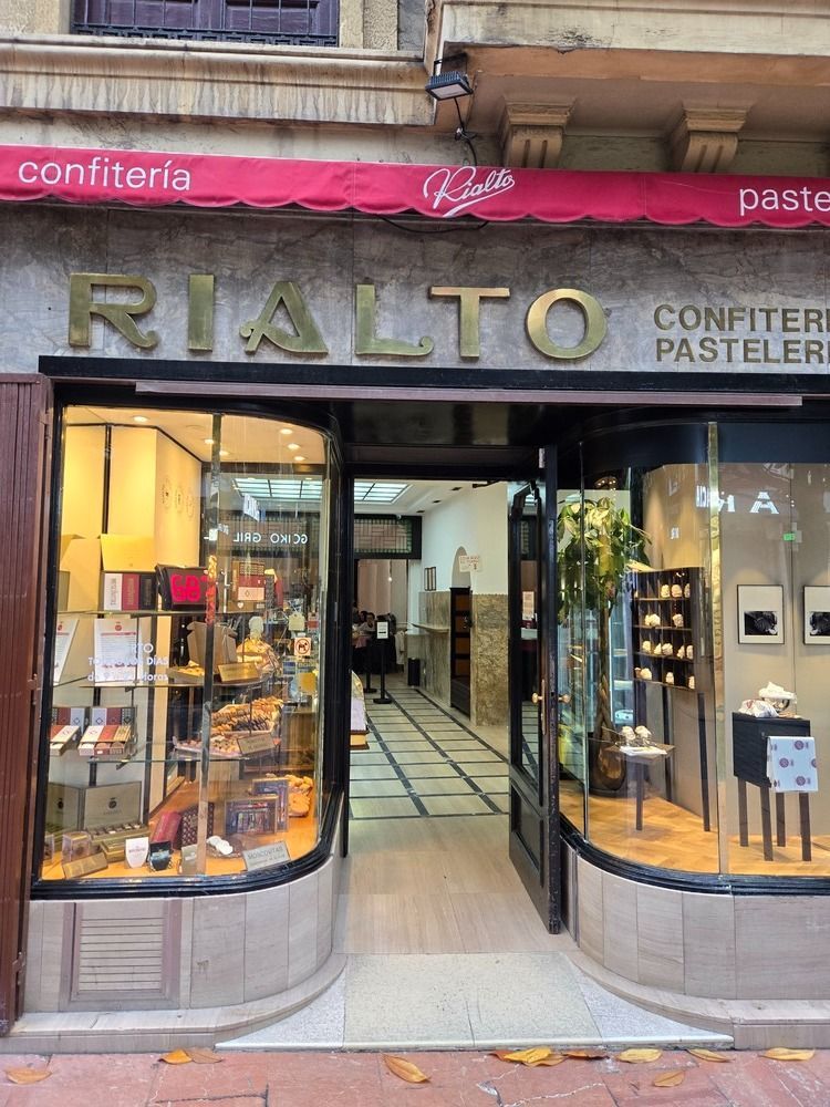 Fachada de la confitería Rialto con toldo, escaparates y puerta abierta.