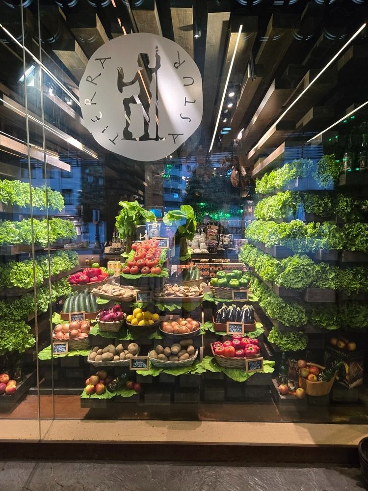 Exhibición de productos agrícolas con cestas escalonadas de coloridas frutas y verduras, pared verde exuberante.