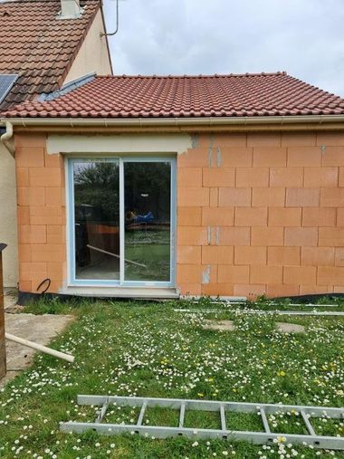 Mur de patio dans la cour arrière avec porte coulissante en verr et toit de tuiles rouges.
