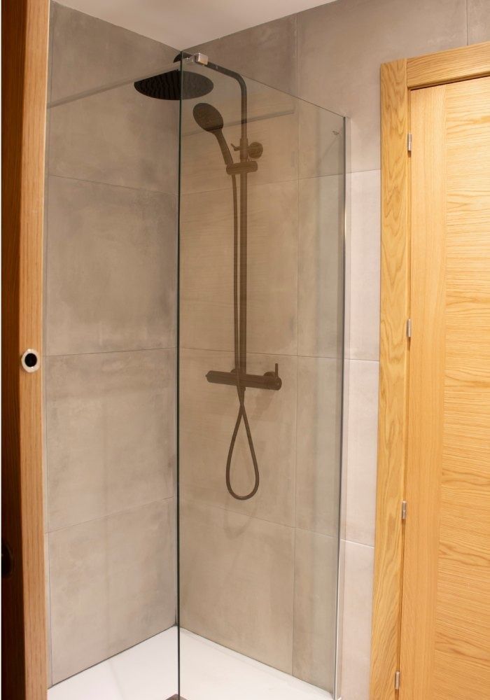Un baño con ducha a ras de suelo y puerta de madera.