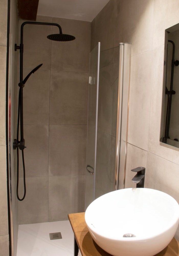 Un baño con lavabo, ducha y espejo.