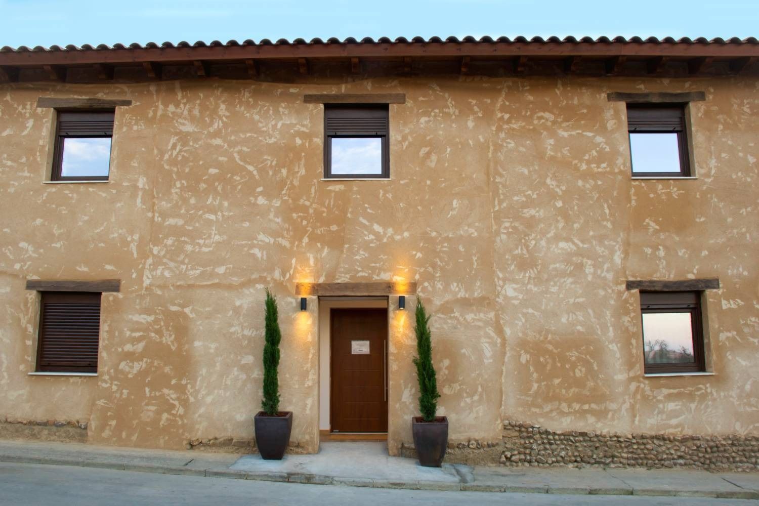 Una casa con dos plantas en macetas delante de ella.