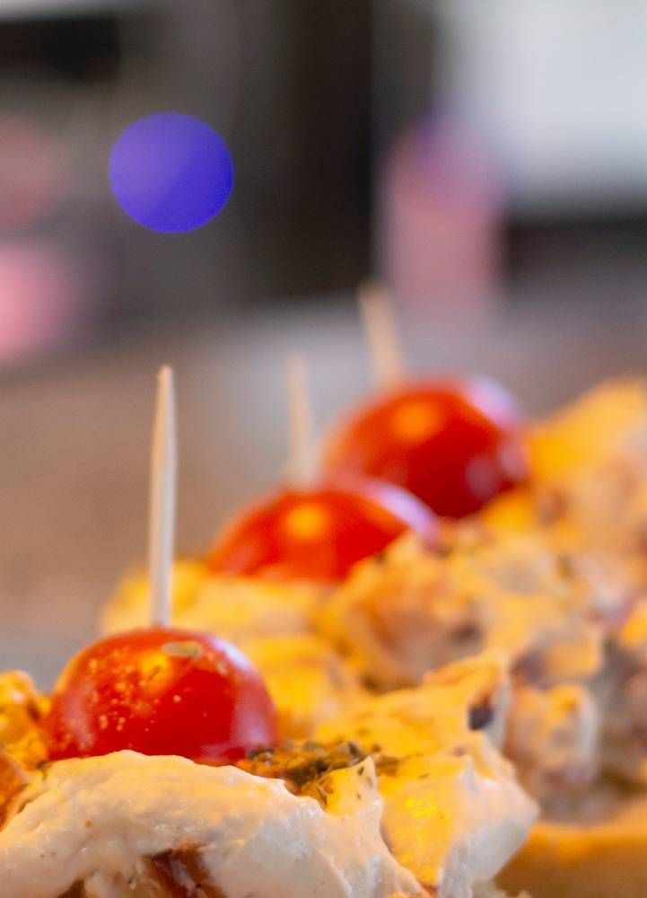 Un primer plano de una pizza con tomates en palillos sobre una mesa.