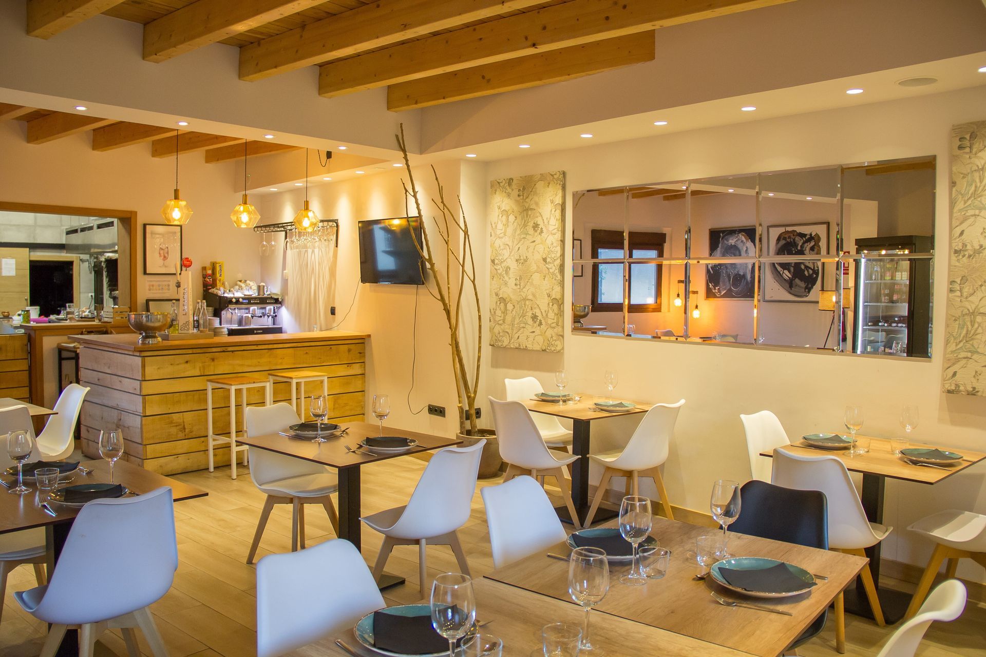 Un restaurante con mesas y sillas y un bar al fondo.