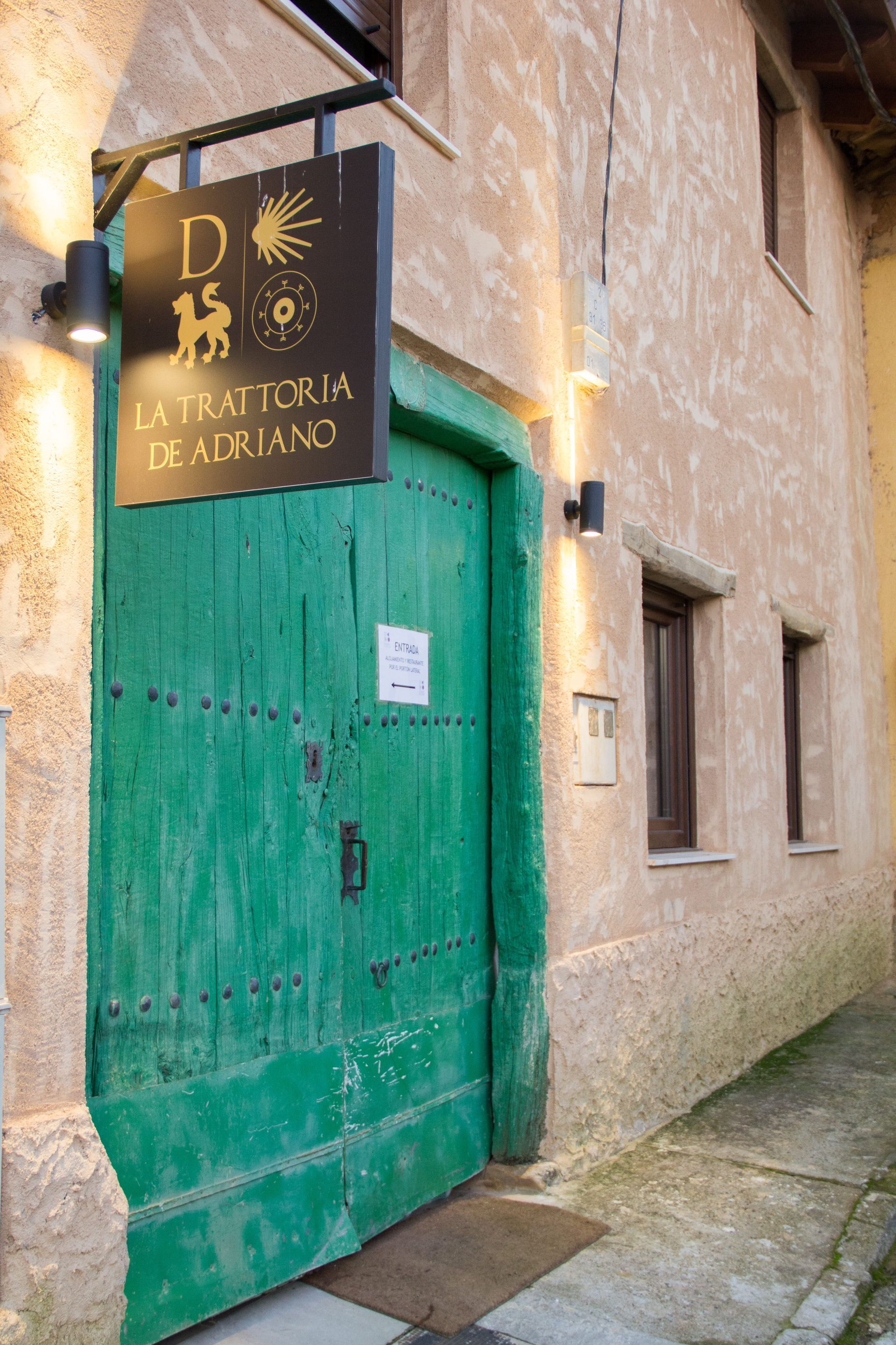 Una puerta verde con un cartel encima que dice La Trattoria de Adriano.