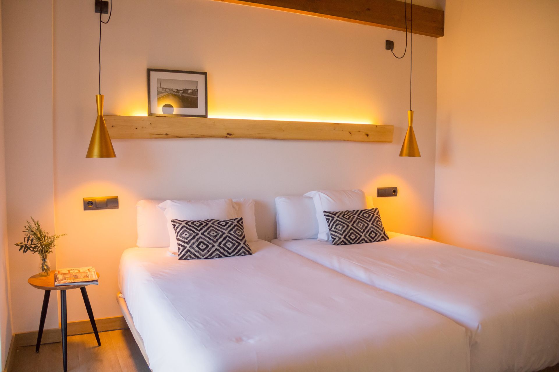 Una habitación de hotel con dos camas y dos lámparas colgando del techo.