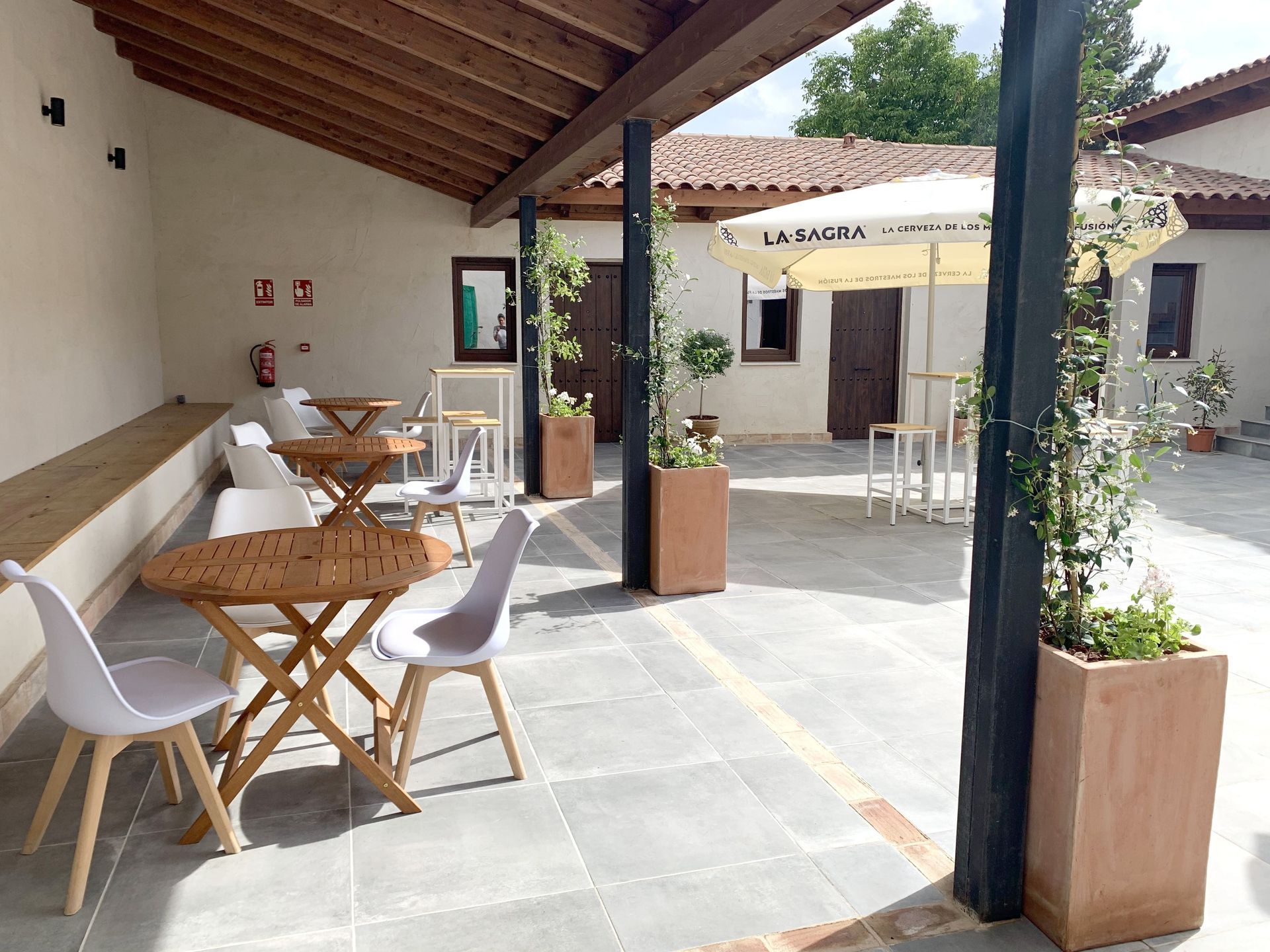 Un patio con mesas y sillas y una sombrilla.