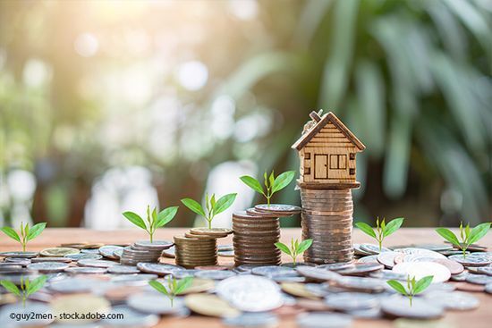 Stapel Kleingeld mit einem Miniaturhaus