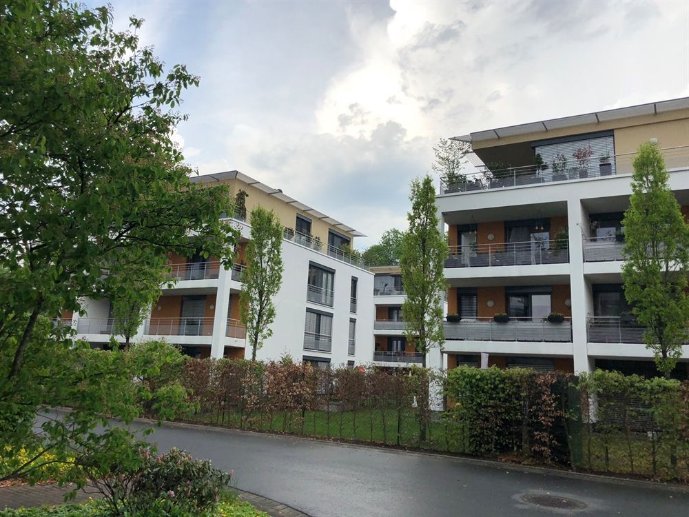 Eine Reihe von Mehrfamilienhäusern mit Balkonen und Bäumen davor