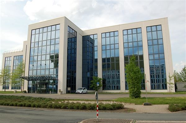 Ein großes Gebäude mit vielen Fenstern und einem davor geparkten Auto