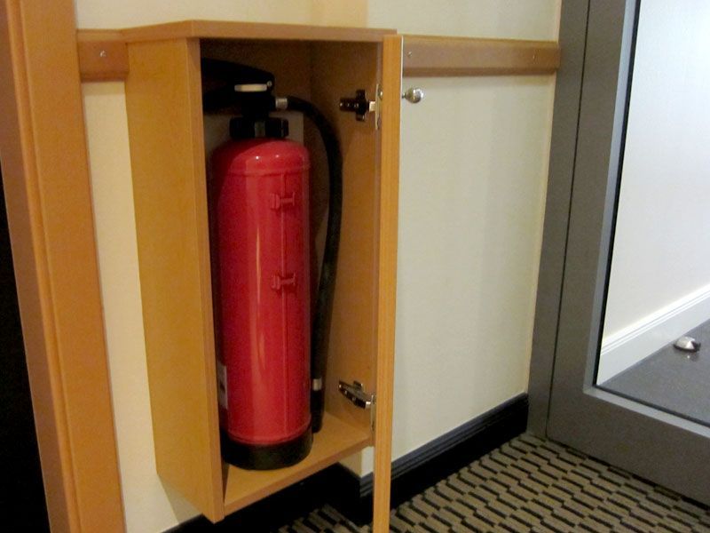 Ein roter Feuerlöscher liegt in einem Holzschrank