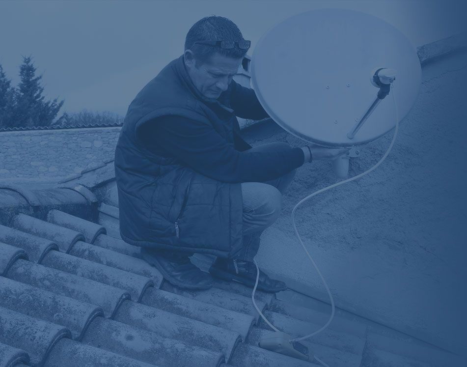 Technicien orientant une antenne satellite