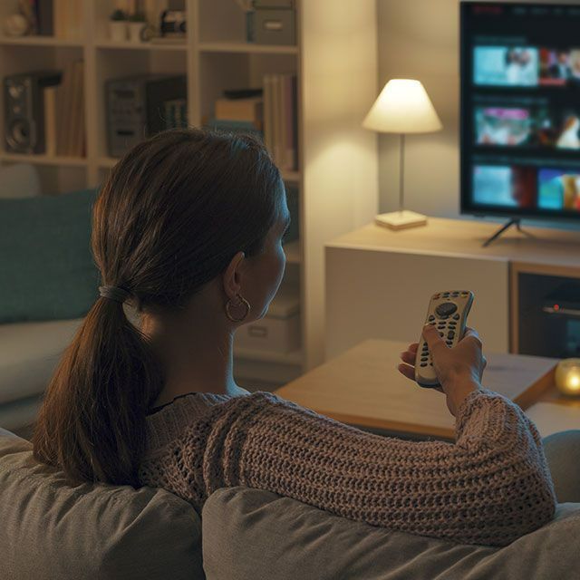 Femme regardant la télévision une télécommande à la main