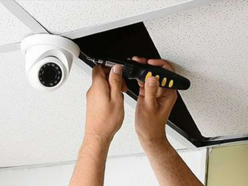 Technicien installant une alarme dans un faux plafond