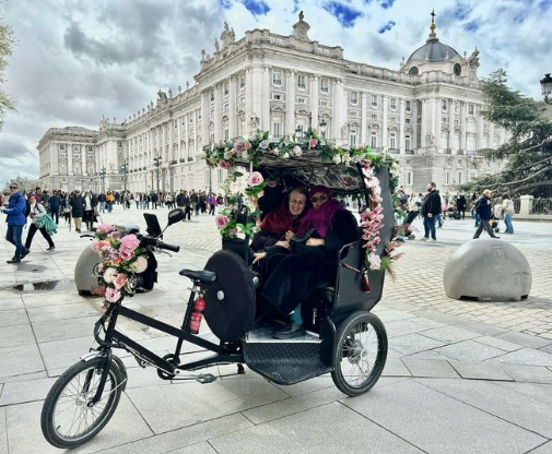Una bicicleta con flores está estacionada frente a un edificio.