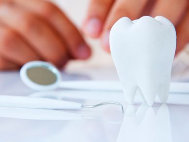 Un modelo de un diente está sobre una mesa al lado de instrumentos dentales.