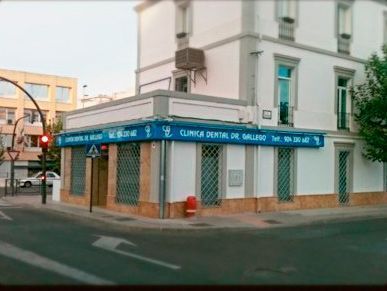 Un edificio blanco con un cartel azul que dice clínica dental de seguro.