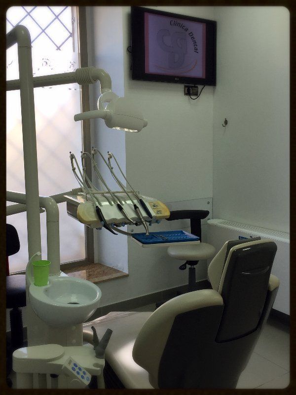 Una imagen de un consultorio dental con un televisor encima de la silla.