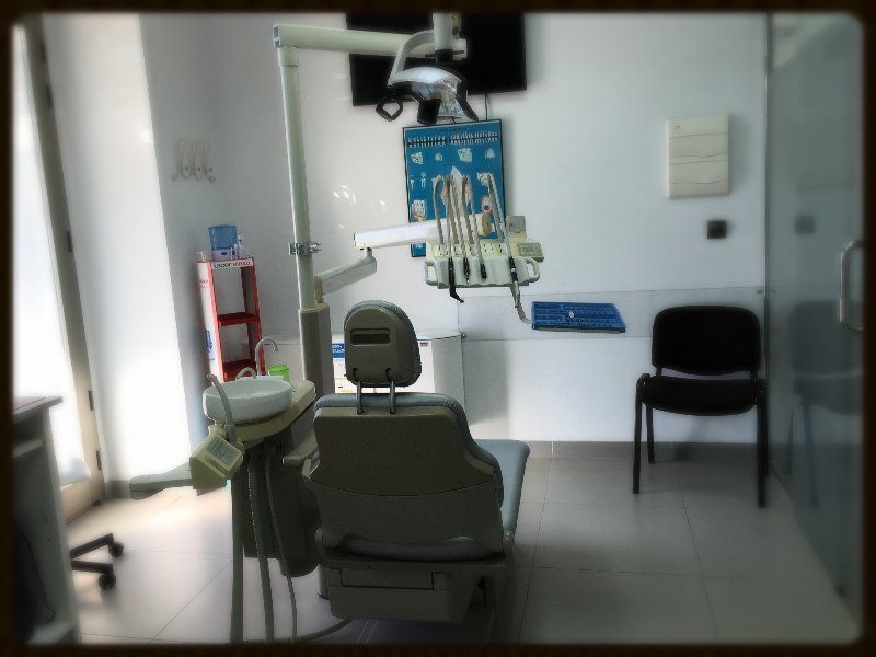 Un consultorio dental vacío con una silla y un lavabo.