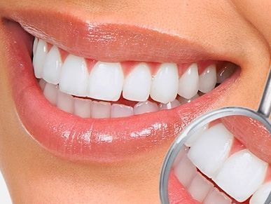 Un primer plano de los dientes de una mujer con un espejo dental.