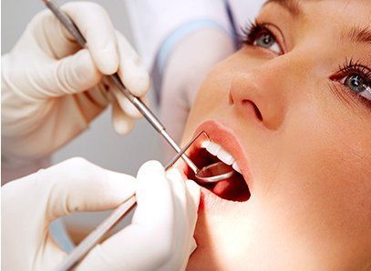 Una mujer se hace examinar los dientes por un dentista.