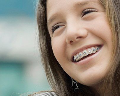 Una niña con aparatos dentales está sonriendo.