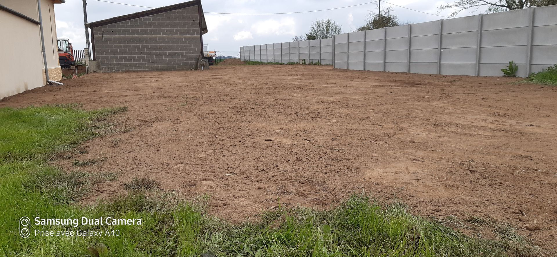 Terrain en terre avec de l'herbe et des palissades grises