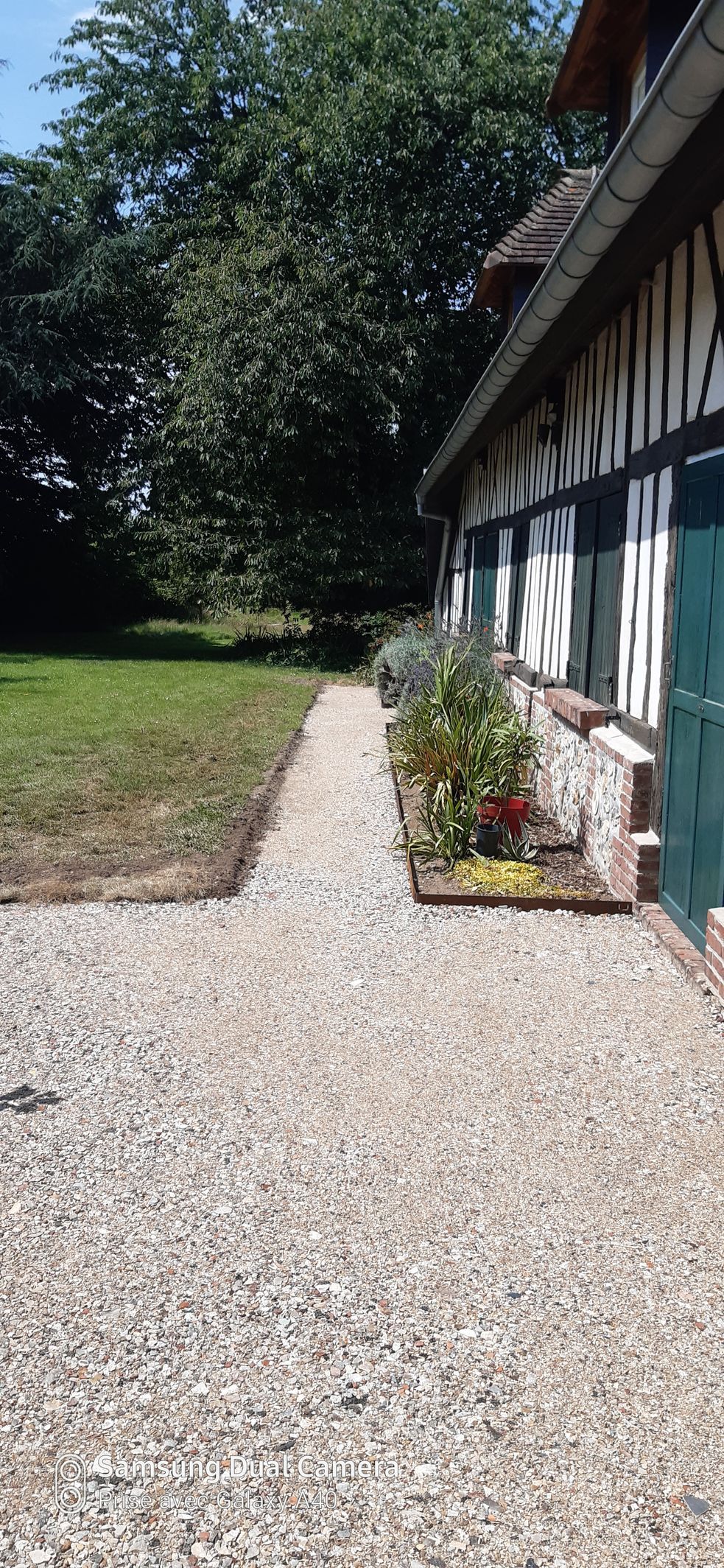 Allée extérieure d'une maison en gravier avec un morceau de pelouse
