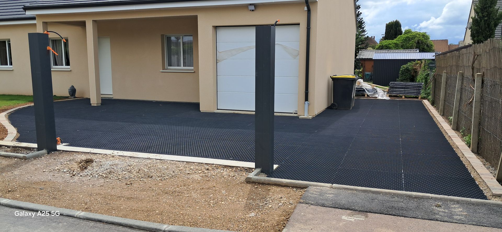 Une allée en cours de construction devant une maison brun clair.