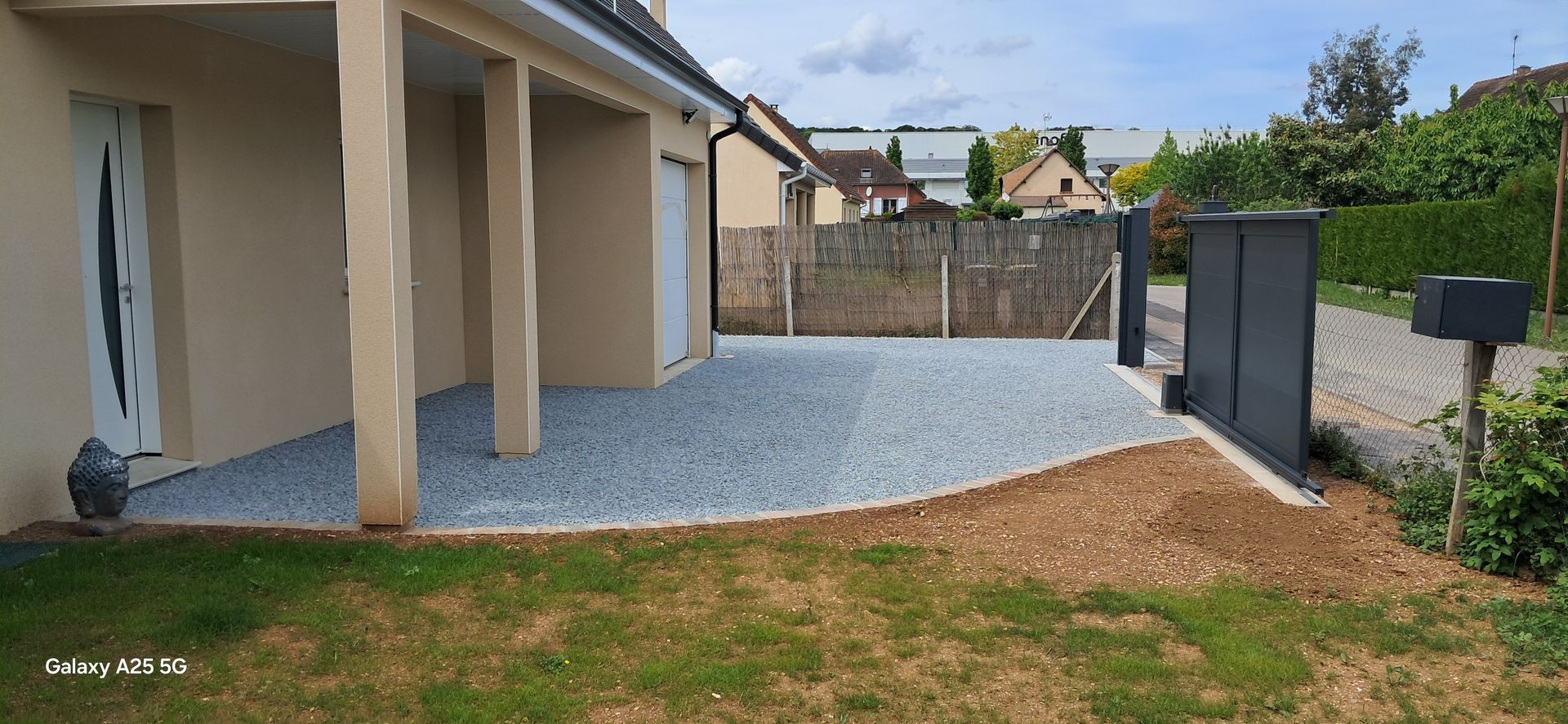 Une allée en graviers gris clair devant un garage.