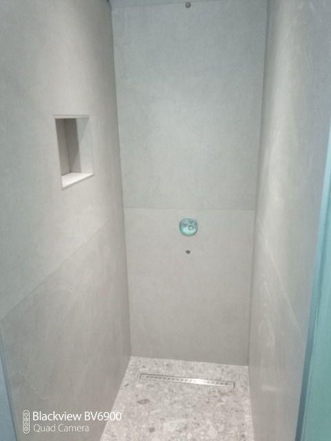 Espace de douche carrelé sol et murs.