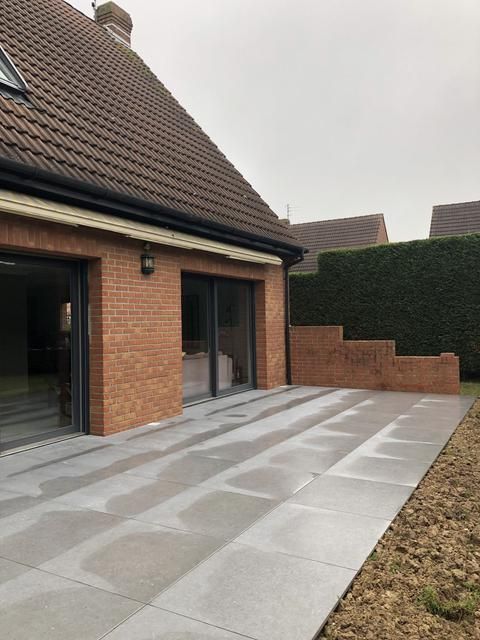 Terrasse carrelée devant maison.