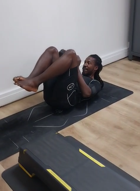 Trois personnes font de l'exercice ensemble dans une salle de sport lumineuse, souriant autour d'une machine.