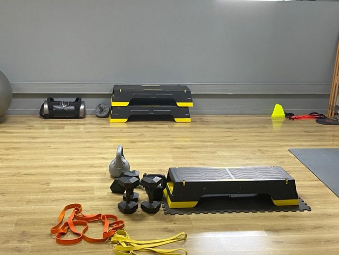 Équipements de sport sur un sol en bois avec des plateformes noires et jaunes, des cônes et des tapis de sol.