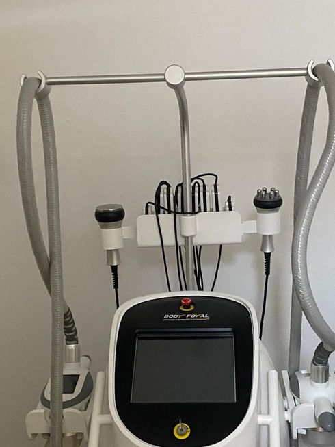 Appareil de soin blanc avec pièces à main et tuyaux intégrés, sur un support.