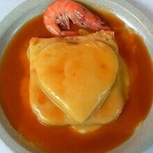 Sobremesa de creme em formato de coração com camarão em molho de laranja em um prato branco.