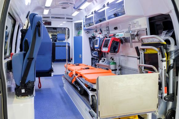 Intérieur d’une ambulance avec un brancard, du matériel médical et des rangements tout le long.