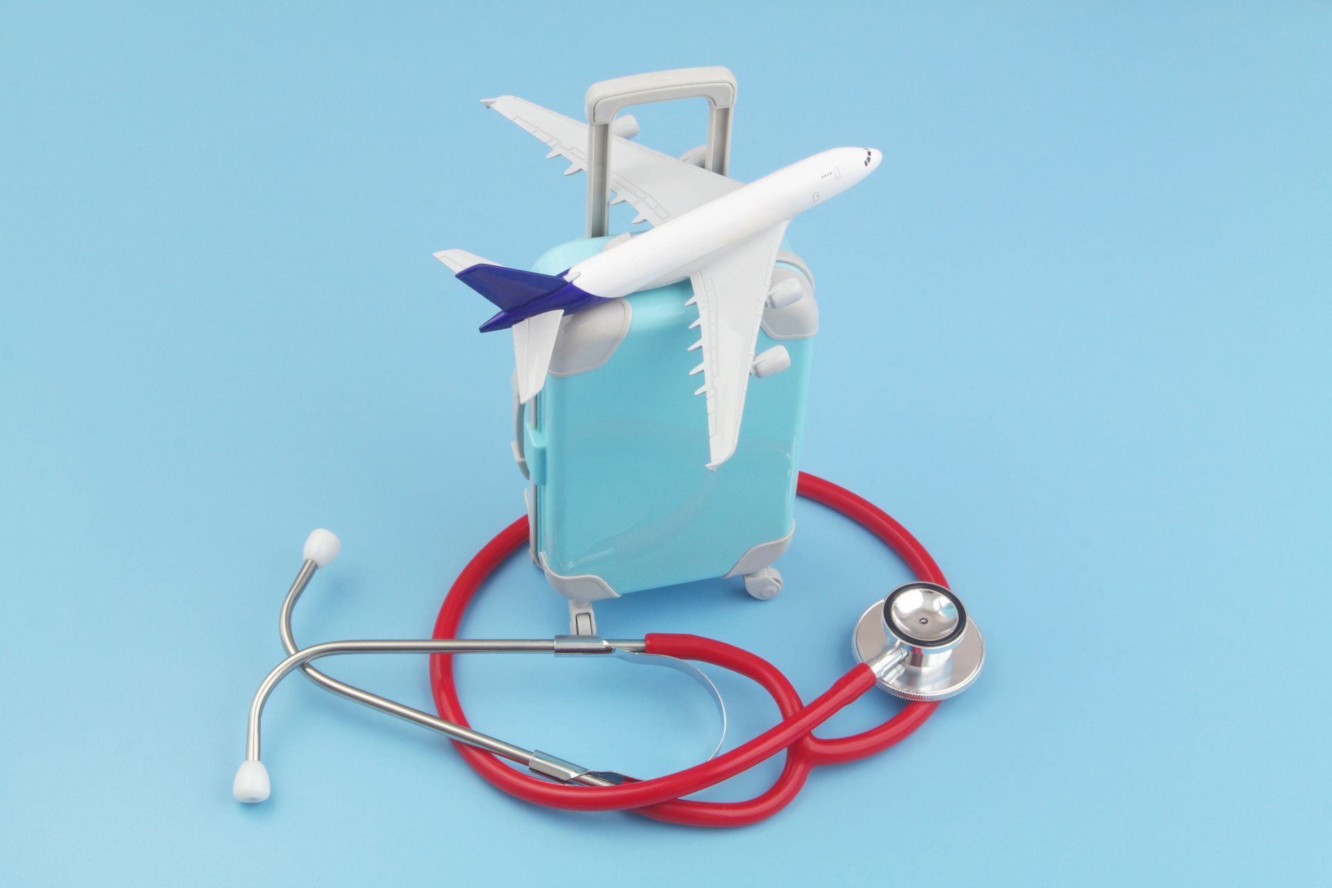 Avion-jouet à côté d’un stéthoscope rouge sur fond bleu.
