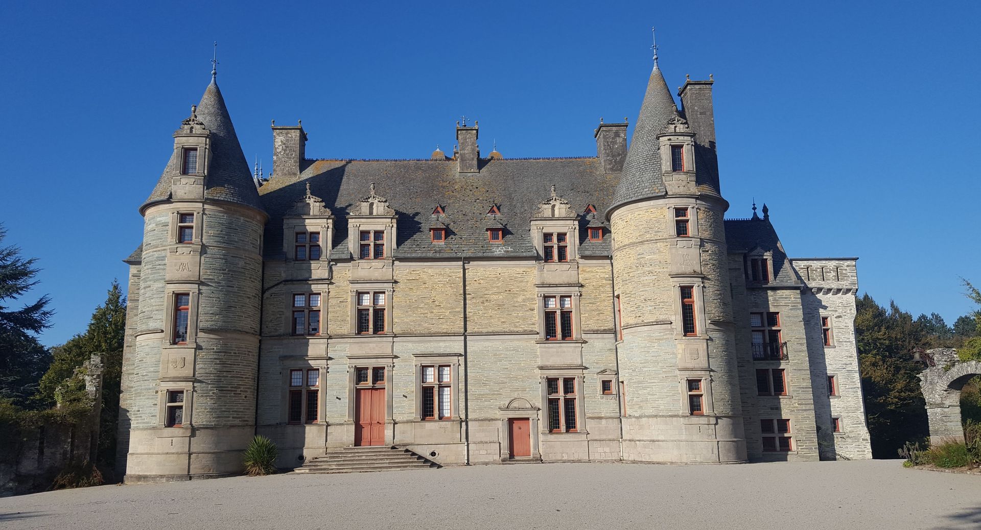 Château de pierre à tourelles sous un ciel bleu limpide.
