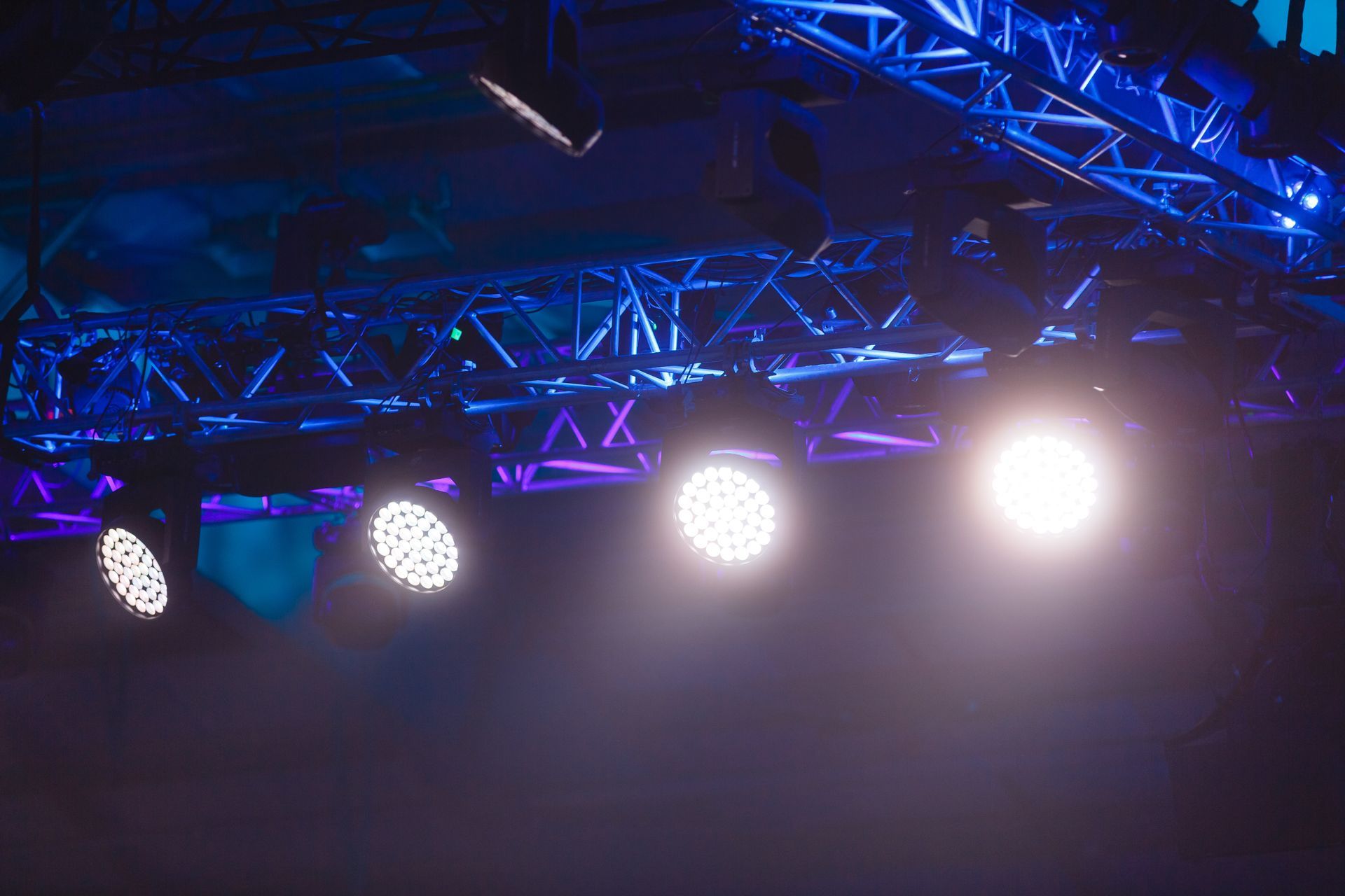 Les projecteurs de scène brillaient intensément, illuminant l'air brumeux de teintes blanches, bleues et violettes.