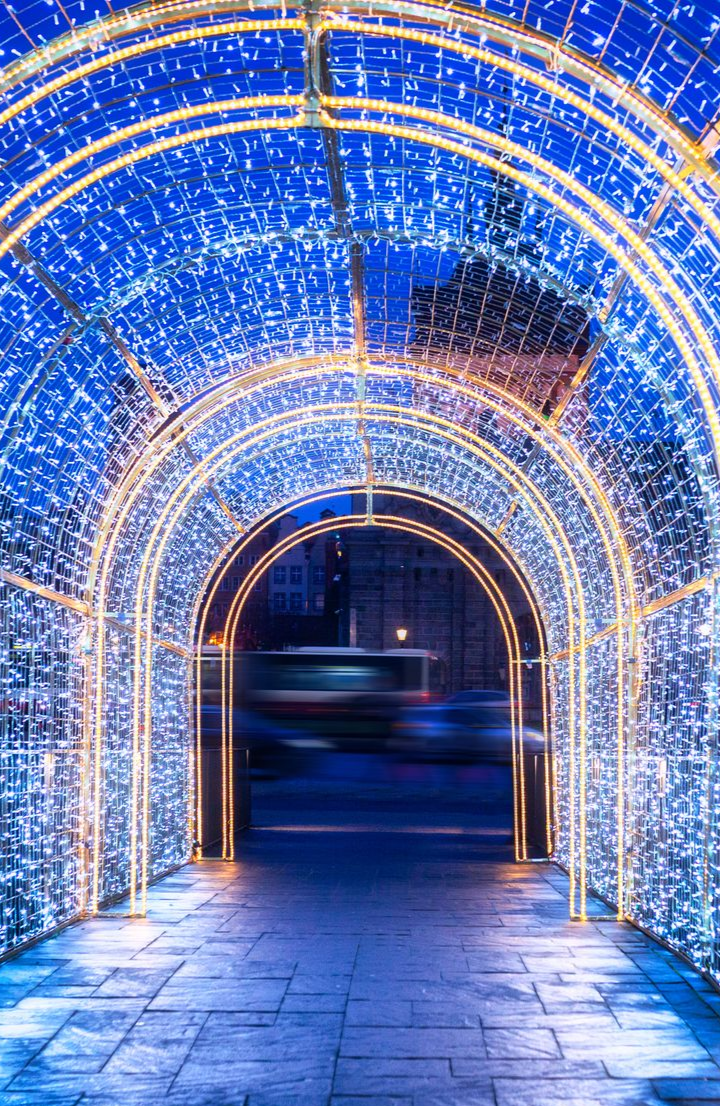 Une arche de lumières bleues scintillantes mène à une scène de rue floue.