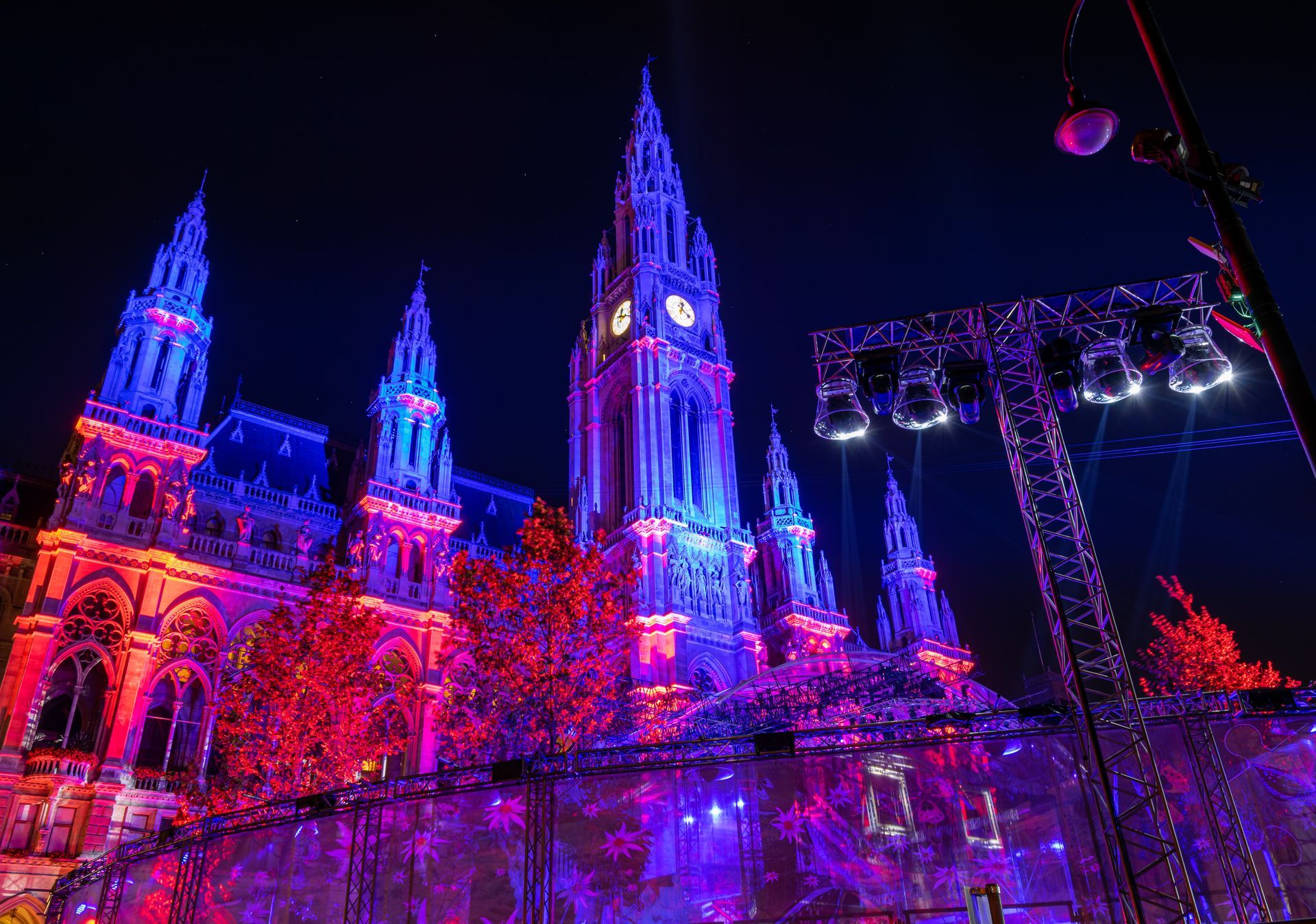 Hôtel de ville illuminé de lumières rouges et bleues la nuit, scène devant.