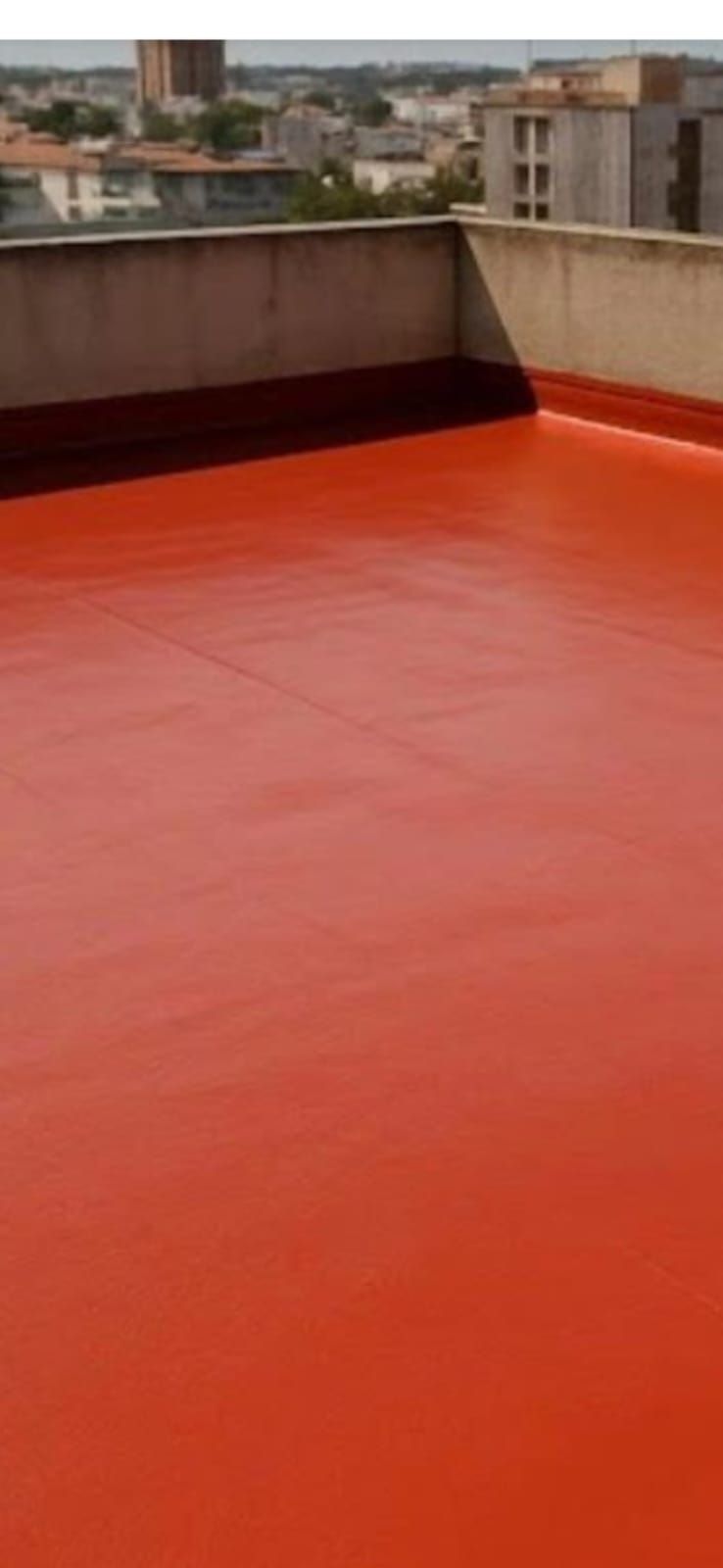 Azotea pintada de rojo con edificios de la ciudad al fondo.