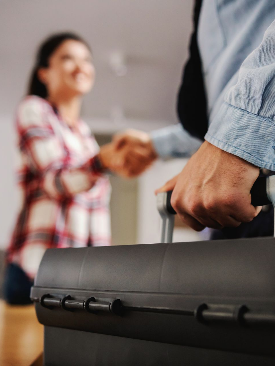 Un homme tenant une boîte à outils noire serre la main d'une femme.